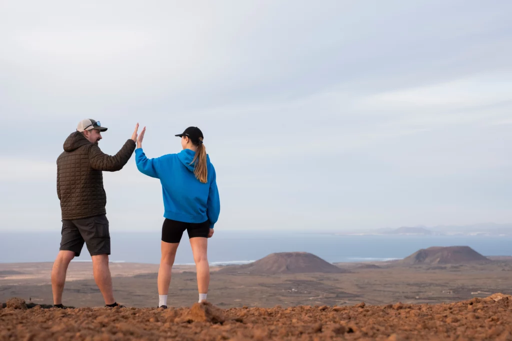 Homme et femme qui se tape dans les mains dans un paysage désertique car content de leurs performances suite au traqueur et l'analyse d'énergie.